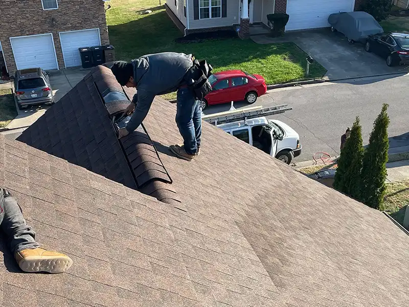 URCovered Construction workers installing the last of the light brown shingles on a residential roof